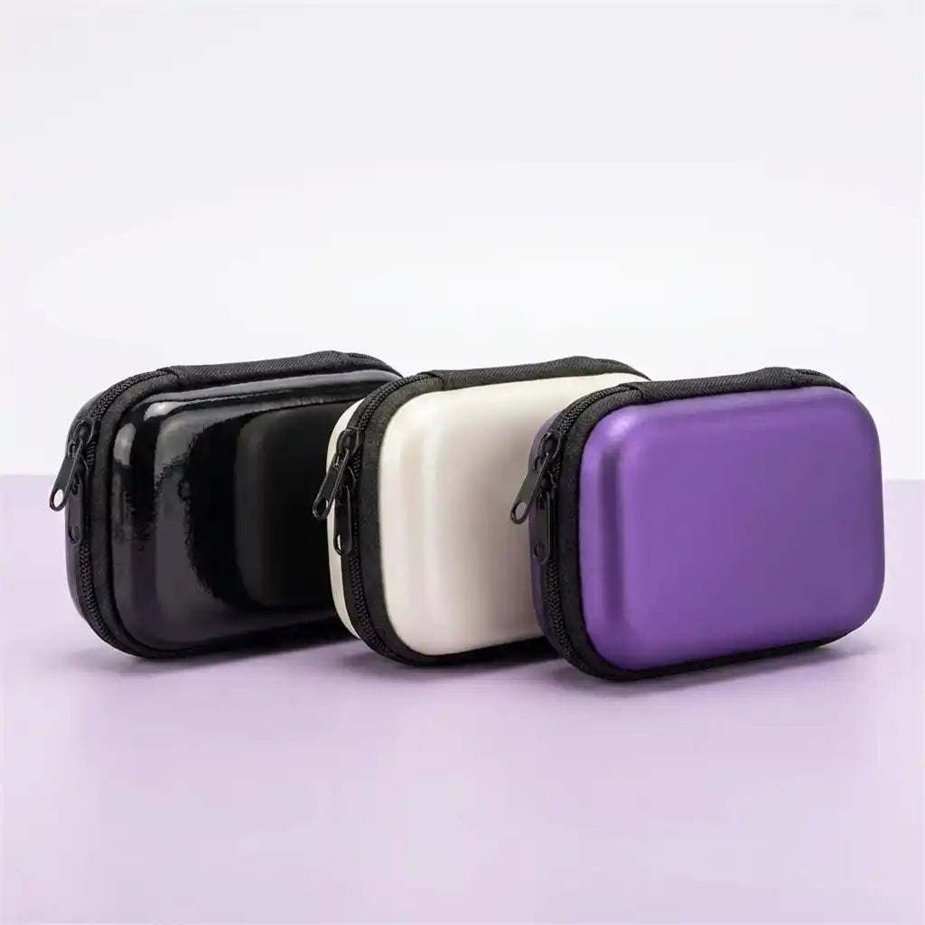Pocket Retro travel case shown in all three colours - glossy black, cream white and metallic purple - with the all-round zip visible